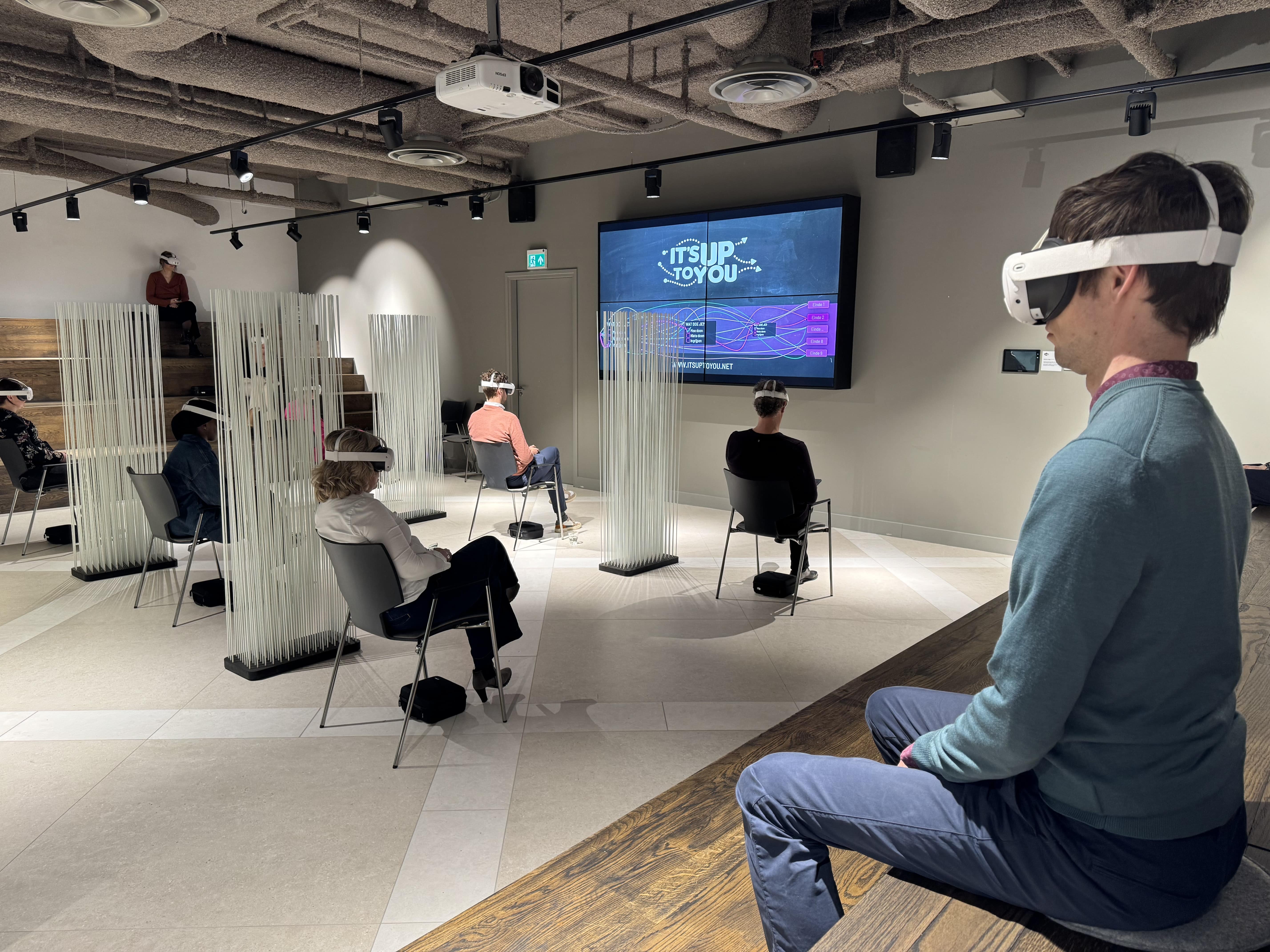 Participants experiencing an IT'S UP TO YOU VR simulation in a training room